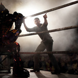 At Crash Palace, an underground robot fight club, Charlie (HUGH JACKMAN) instructs his former league bot Noisy Boy (left), pitted against backroom brawler Midas, in this scene from REAL STEEL.