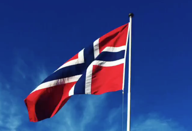 Det norske flagg med blå himmel i bakgrunnen.