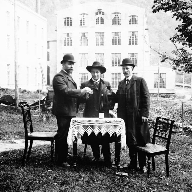 Fotograf og spinnerimeister Wilhelm Salberg (til venstre) og to ukjende menn skålar framfor bomullsfabrikken i Dale, kring 1910. Foto: Wilhelm Salberg