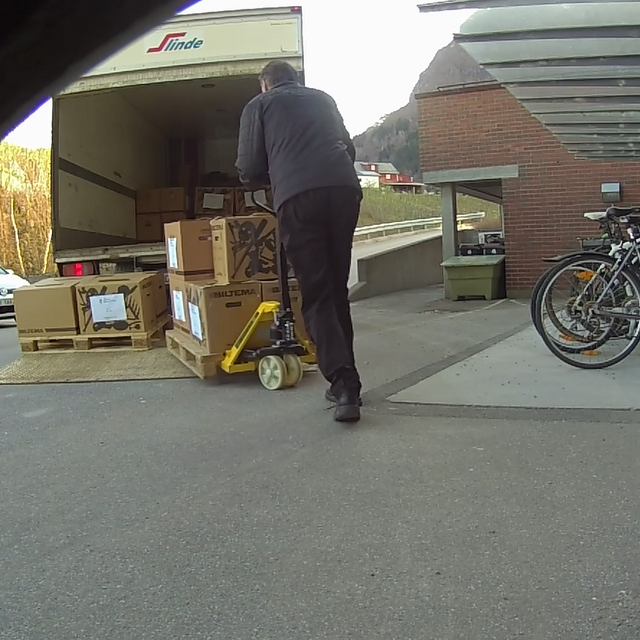 Ein mann lastar kasser inn i ein lastebil.