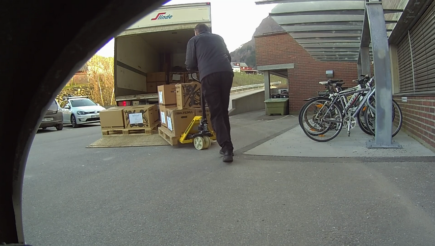 Ein mann lastar kasser inn i ein lastebil.