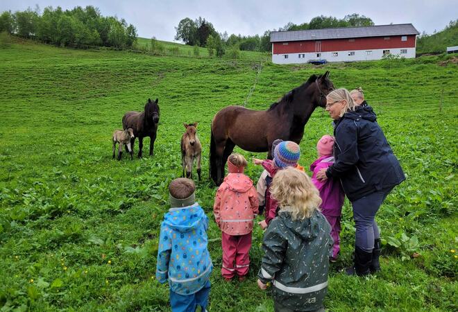 Barn med hest og gård i bakgrunnen.