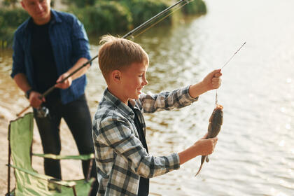 Showing the catch. Father and son on fishing together outdoors a