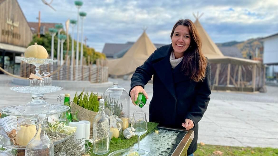 Festivalsjef Monica Østenheden sjenker i glass på Matlyst-bordet på torget i Brumunddal