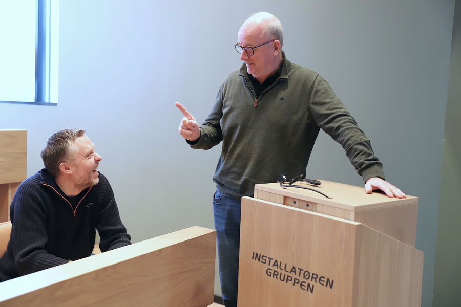 Ved å ta hånd om både teori og praksis i bedriften, føler lærlingene i større grad at de er på jobb også i klasseromsundervisningen. Det gir en viktig følelse av tilhørighet, sier Installatøren Fredrikstads administrative leder Geir Bakken og skolens leder Per Tore Solberg. Her gir Solberg noen belærende ord til Bakken - på fotografens oppfordring. 