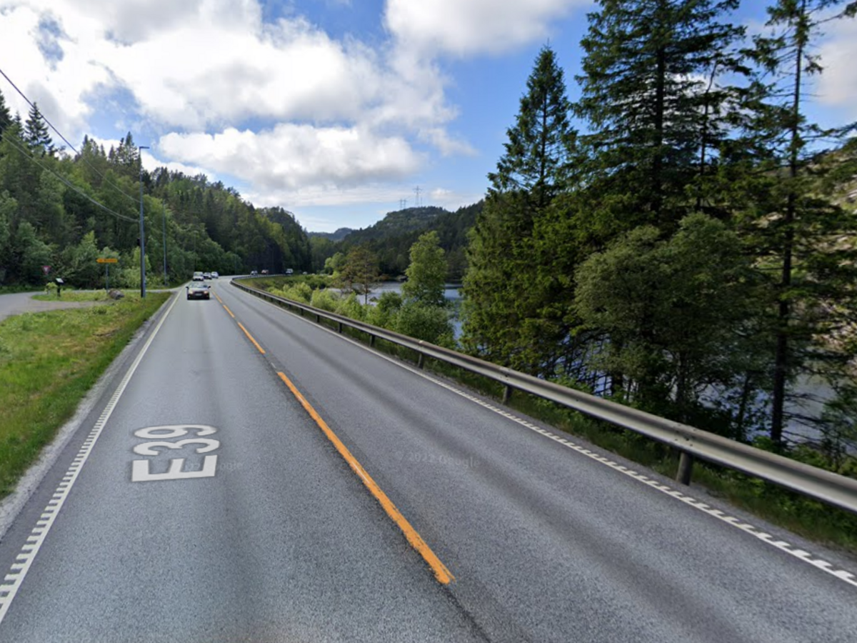 Bilde av E39 på vei ut av Fosselandstunnelen i retning Flekkefjord. Biler, asfalt, blå himmel og trær.