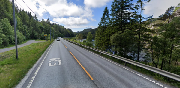 Bilde av E39 på vei ut av Fosselandstunnelen i retning Flekkefjord. Biler, asfalt, blå himmel og trær.