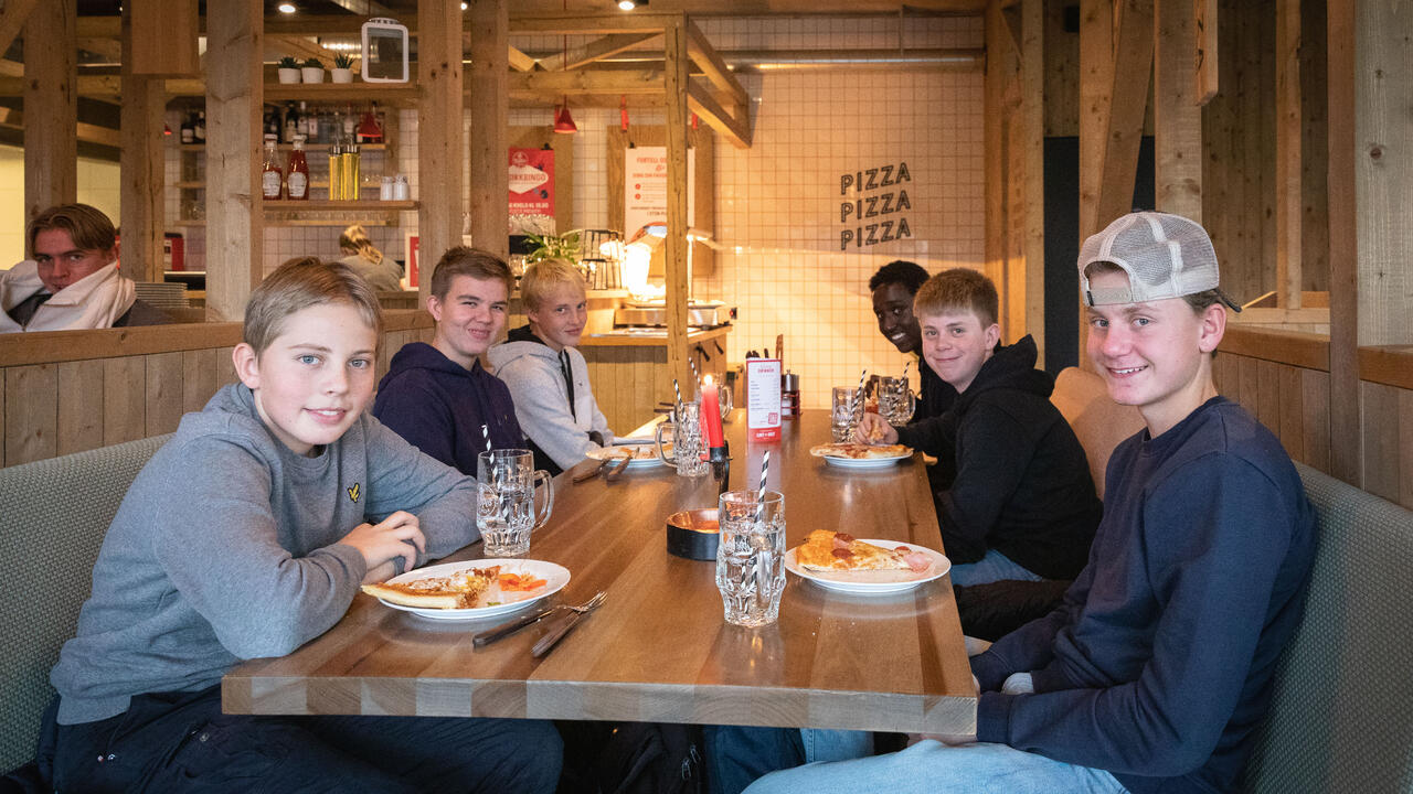 Foto av ungdommer som sitter rundt et bord og spiser pizza