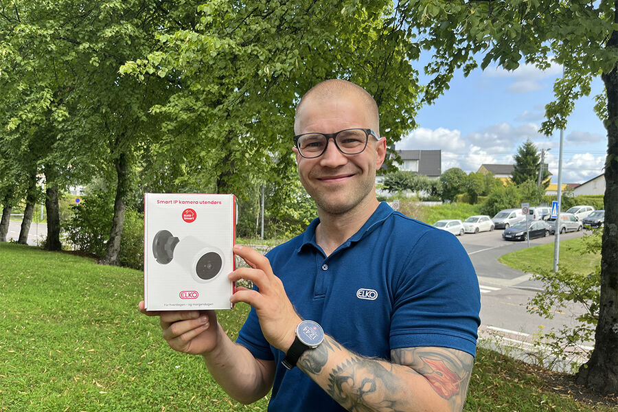 Christoffer Borgersen Strand i ELKO AS viser oss ELKO sitt nye, nettilkoblede utendørskamera. Toveiskommunikasjon, fleksibilitet med tanke på fokusmuligheter og IP-graden er tre av de mange egenskapene som gjør det egnet til både hjemme- og hyttebruk. Foto: Tone Strand, ELKO AS.