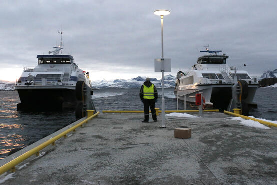 To hurtigbåter ved den nye kaia på Sørarnøy. Mann med refleksvest venter på kaia.