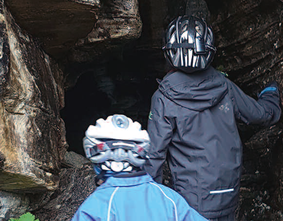 To barn med hjelmer på vei inn i en grotte