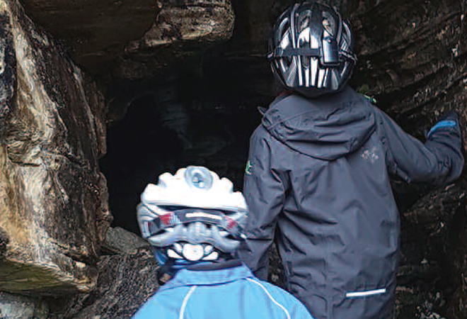 To barn med hjelmer på vei inn i en grotte