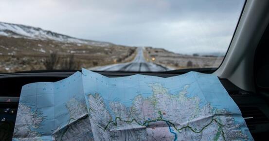 Landskap sett gjennom frontrute, med kart i forkant Foto: Språkrådet/Tabea Schimpf - Unsplash