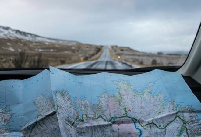 Landskap sett gjennom frontrute, med kart i forkant Foto: Språkrådet/Tabea Schimpf - Unsplash