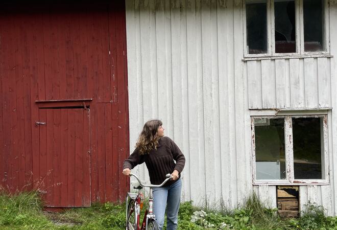 Bilde: Sykkel med på kjøpet. Prosjektleder i Lys i Gamle Hus i Heim, Runa Tunheim poserer med en gammel flott sykkel som matcher huset og følger med huset.