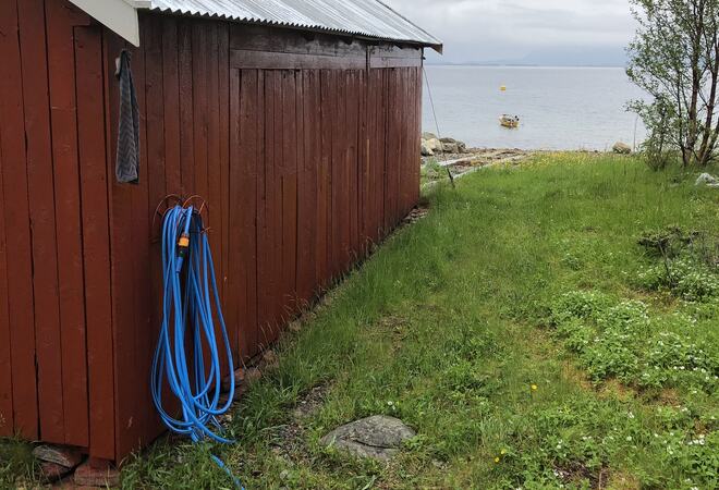 Naust ved sjøen og med en gresseng ved siden