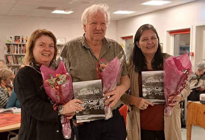 Lill Hilde Kaldager, Bjørnar Thoresen og Svanhild Lind står ved siden av hverandre på biblioteket. Alle tre har fått blomster.