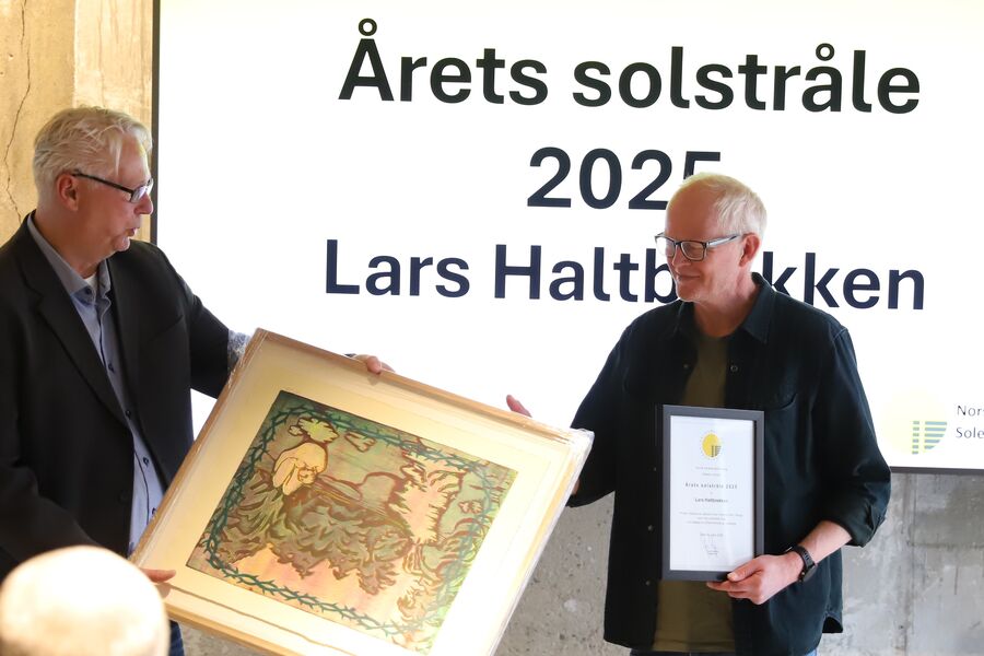 Lars Haltbrekken får overrakt diplom og gave for sin innsats for solenergi. 