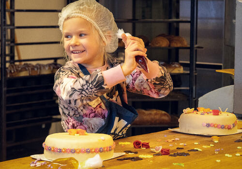 Jente som pynter kake på bakeriet